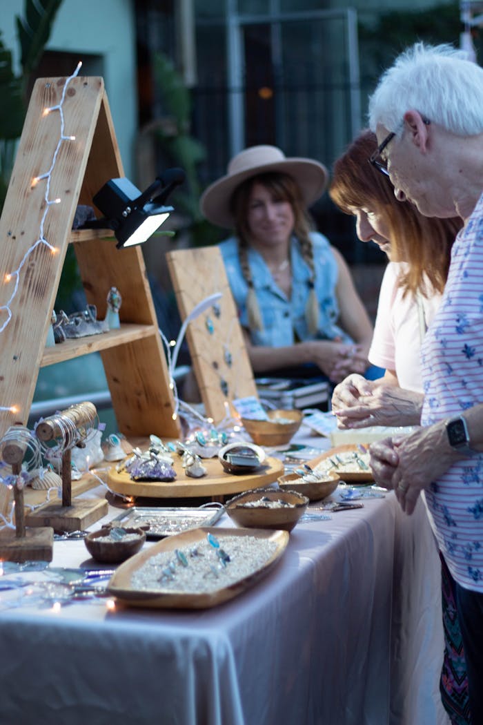 gallery-2 Shoppers browse handcrafted jewelry at an outdoor artisan market stall.