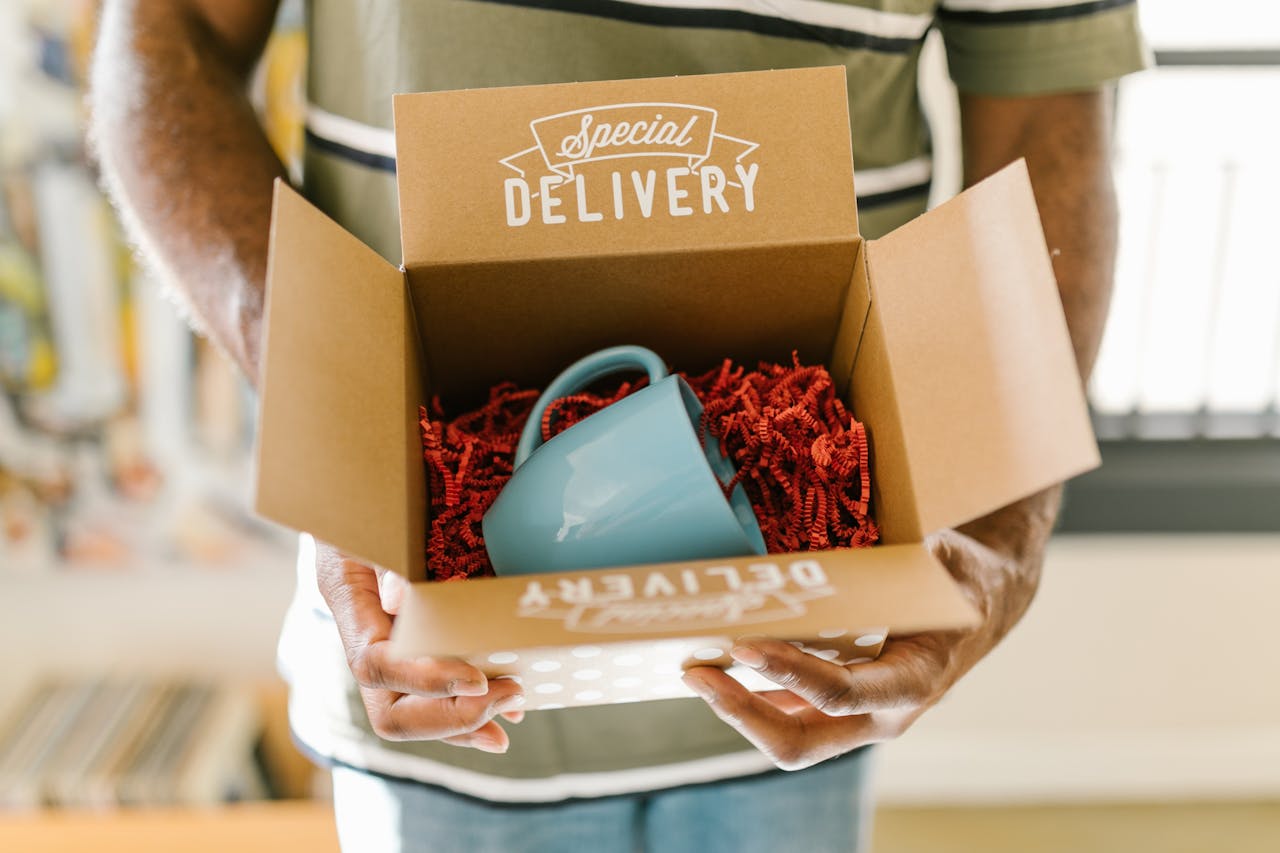 gallery-6 Man holding a box with a special delivery coffee mug inside.